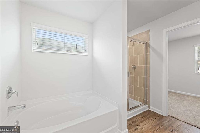 full bathroom with a bath, a shower stall, wood finished floors, and baseboards