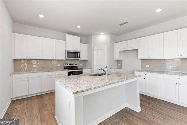 kitchen featuring wood finished floors, stainless steel appliances, white cabinets, and a sink