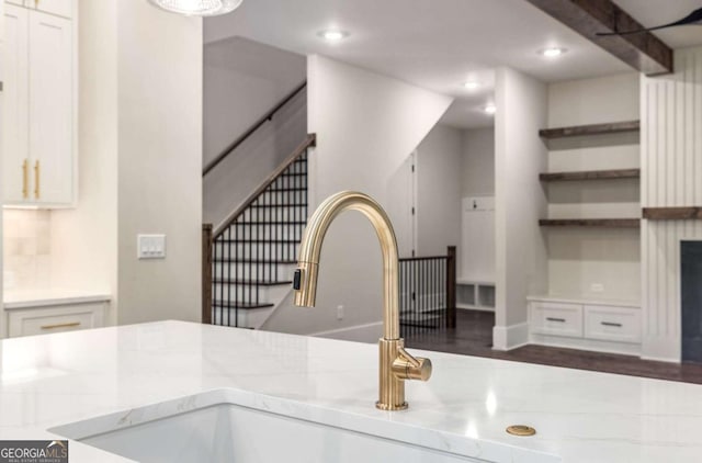 interior details with open shelves, light stone countertops, recessed lighting, and a sink