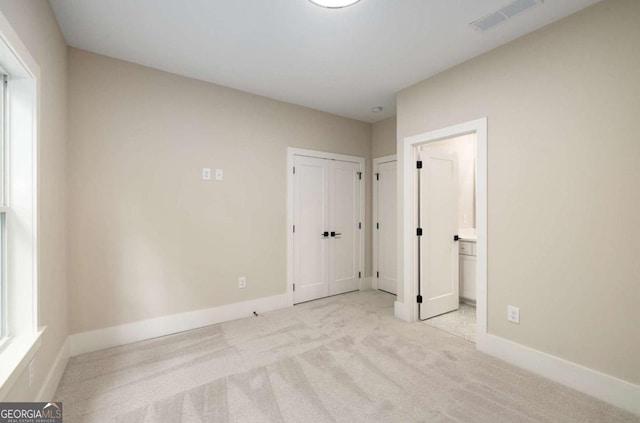 unfurnished bedroom featuring connected bathroom, visible vents, carpet floors, and baseboards