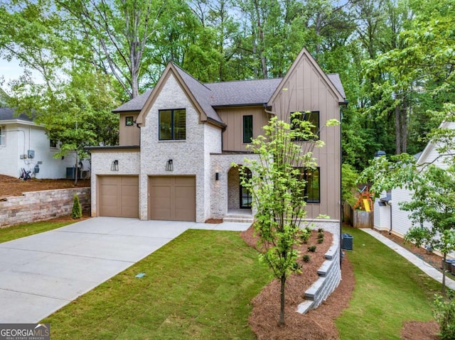 view of front of house with concrete driveway, board and batten siding, roof with shingles, a front yard, and an attached garage