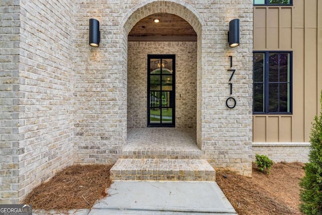 doorway to property with board and batten siding and brick siding