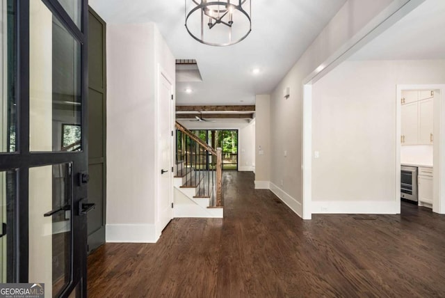 foyer entrance featuring beverage cooler, wood finished floors, stairs, and baseboards