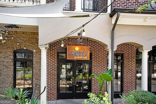 view of exterior entry featuring brick siding and french doors