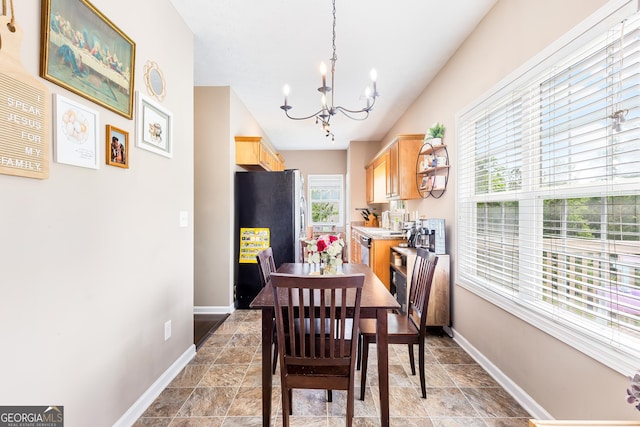 dining space featuring stone finish floor, a chandelier, and baseboards