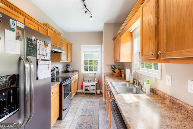 kitchen with a sink, appliances with stainless steel finishes, under cabinet range hood, and a healthy amount of sunlight