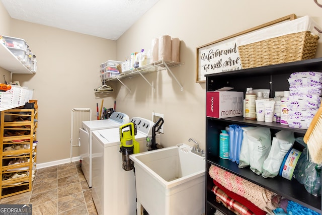 washroom featuring stone finish floor, a sink, baseboards, washer and clothes dryer, and laundry area
