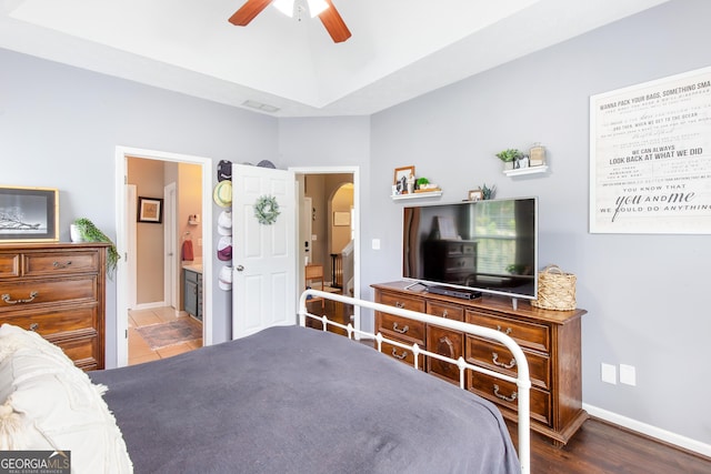 bedroom featuring ceiling fan, arched walkways, baseboards, wood finished floors, and ensuite bath