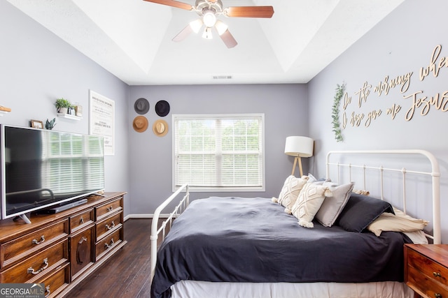 bedroom featuring a raised ceiling, visible vents, ceiling fan, and dark wood-style floors