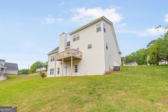 rear view of property featuring a chimney, a yard, central AC unit, and a wooden deck