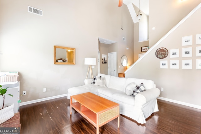 living area with wood finished floors, stairway, baseboards, visible vents, and high vaulted ceiling