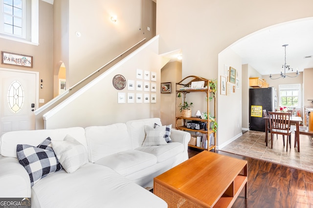 living area featuring a high ceiling, arched walkways, an inviting chandelier, and stairway