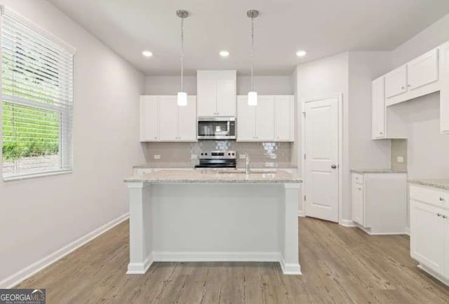 kitchen with light wood-style flooring, decorative backsplash, appliances with stainless steel finishes, white cabinets, and a sink