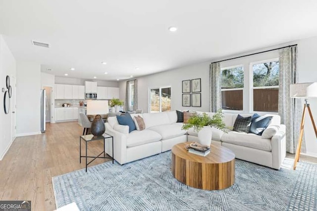 living area with baseboards, recessed lighting, visible vents, and light wood-style floors