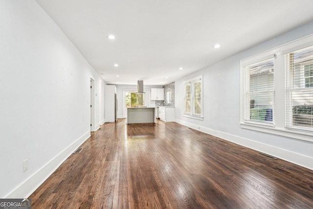 unfurnished living room with visible vents, recessed lighting, baseboards, and dark wood-style floors