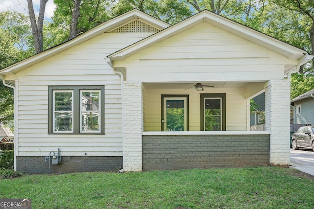 view of front facade with a ceiling fan, covered porch, and a front yard