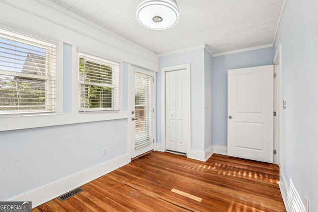 unfurnished bedroom featuring baseboards, ornamental molding, wood-type flooring, and visible vents