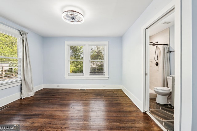 unfurnished bedroom with baseboards, visible vents, multiple windows, and wood finished floors