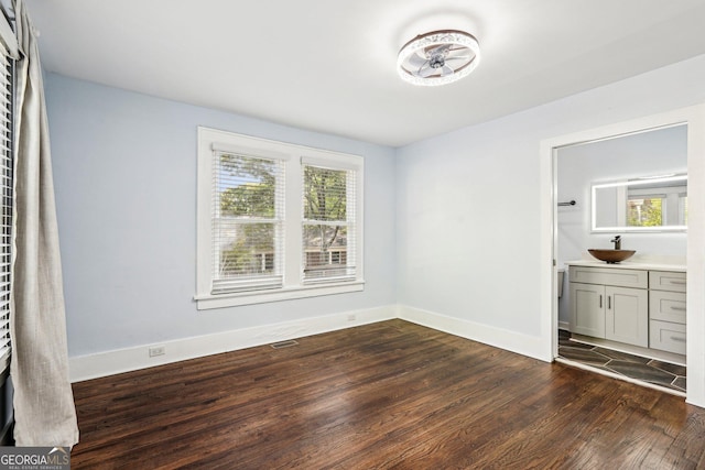 unfurnished bedroom featuring a sink, baseboards, dark wood finished floors, and visible vents