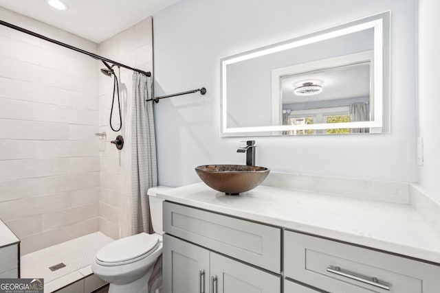 bathroom with vanity, a tile shower, and toilet