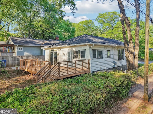 rear view of house featuring a chimney, fence, and a deck