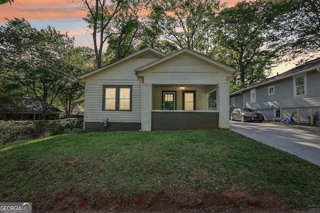bungalow-style home with covered porch and a front yard