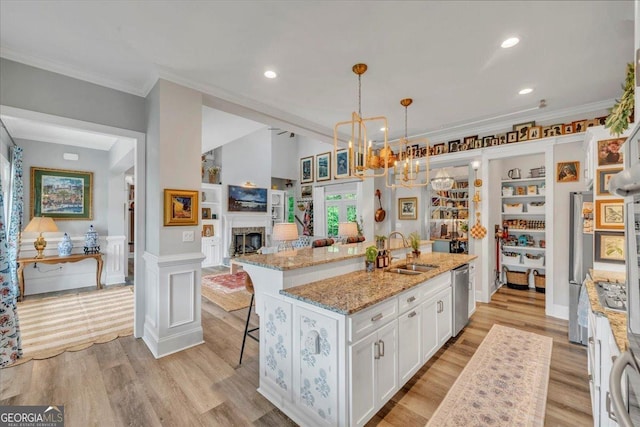 205 River Forest Dr, Forsyth, GA 31029 - kitchen featuring appliances with stainless steel finishes, a sink, ornamental molding, white cabinetry, and an island with sink