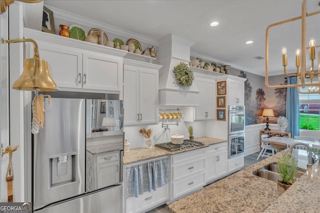 205 River Forest Dr, Forsyth, GA 31029 - kitchen featuring a sink, white cabinets, a chandelier, ornamental molding, and stainless steel appliances