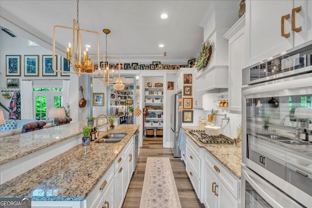 205 River Forest Dr, Forsyth, GA 31029 - kitchen featuring ornamental molding, white cabinetry, a chandelier, a sink, and stainless steel appliances