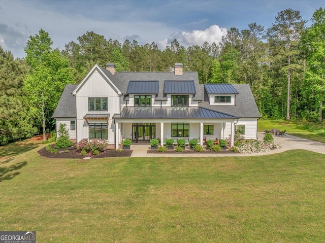 205 River Forest Dr, Forsyth, GA 31029 - view of front of house with covered porch, a front yard, a chimney, a standing seam roof, and board and batten siding