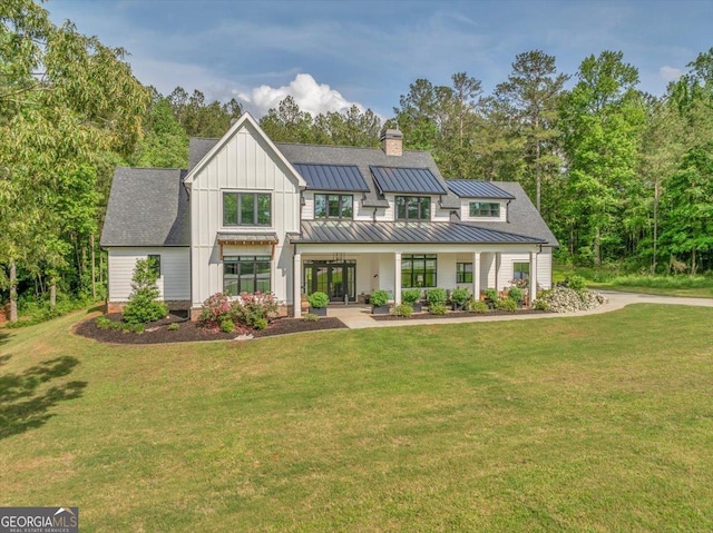 205 River Forest Dr, Forsyth, GA 31029 - back of property with a yard, a standing seam roof, a chimney, and board and batten siding