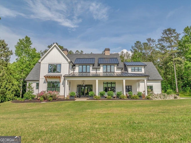 205 River Forest Dr, Forsyth, GA 31029 - view of front of house with a front lawn, french doors, a chimney, and a standing seam roof