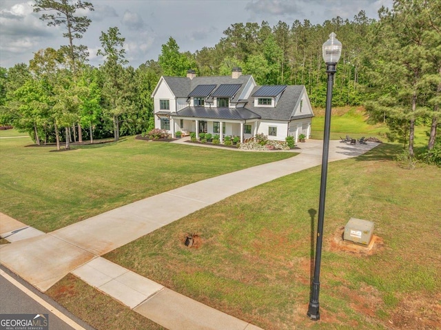 205 River Forest Dr, Forsyth, GA 31029 - view of front of house featuring a standing seam roof, metal roof, a garage, roof mounted solar panels, and a front lawn