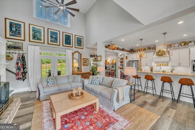 205 River Forest Dr, Forsyth, GA 31029 - living room with light wood-style flooring, ceiling fan with notable chandelier, recessed lighting, a towering ceiling, and ornamental molding