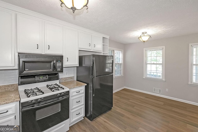 304 N Briar Rdg, Woodstock, GA 30189 - kitchen with freestanding refrigerator, black microwave, light wood-style floors, white cabinetry, and range with gas cooktop