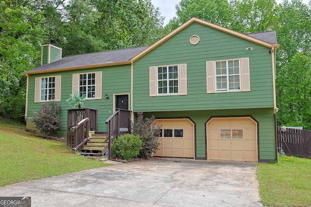 bi-level home featuring a chimney, a front yard, concrete driveway, and an attached garage