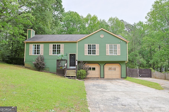 split foyer home featuring a chimney, fence, a front yard, concrete driveway, and an attached garage