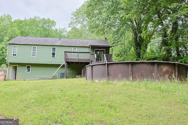 back of house featuring a wooden deck, a yard, and an outdoor pool