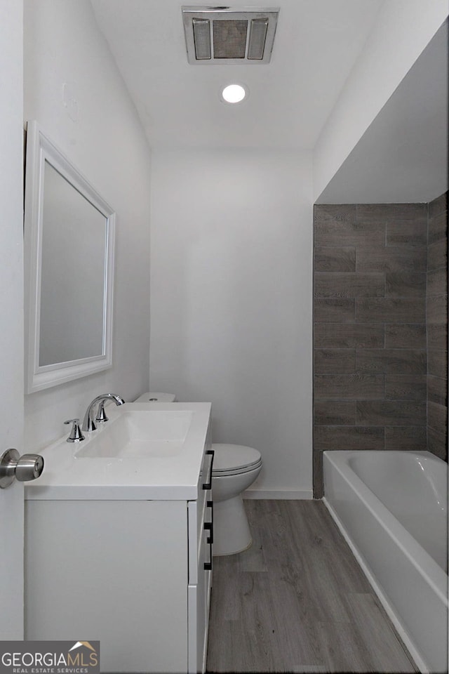 bathroom featuring visible vents, baseboards, toilet, wood finished floors, and vanity