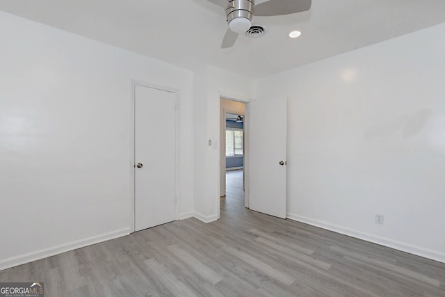 unfurnished room with a ceiling fan, visible vents, wood finished floors, and baseboards