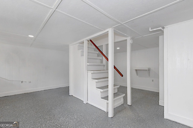 finished basement featuring baseboards and stairway