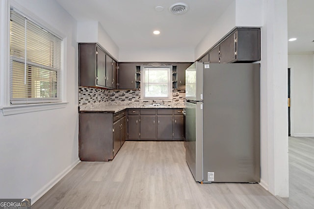 kitchen featuring light wood-style floors, open shelves, tasteful backsplash, dark brown cabinetry, and freestanding refrigerator
