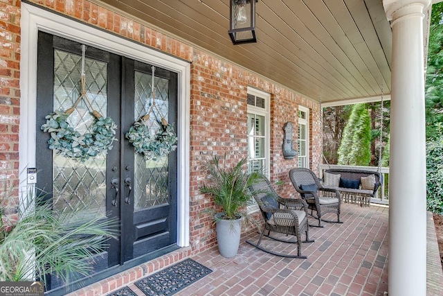 2930 Aquitania Ln, Cumming, GA 30040 - doorway to property featuring brick siding, a porch, and french doors