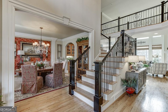 2930 Aquitania Ln, Cumming, GA 30040 - staircase with a chandelier, baseboards, ornamental molding, wood finished floors, and a high ceiling