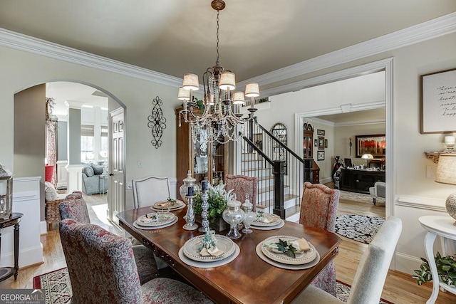 2930 Aquitania Ln, Cumming, GA 30040 - dining area with arched walkways, a chandelier, light wood-style floors, stairway, and crown molding