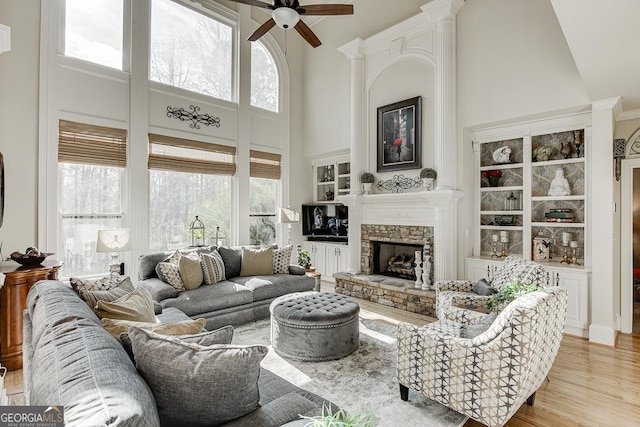 2930 Aquitania Ln, Cumming, GA 30040 - living area with a high ceiling, light wood finished floors, a ceiling fan, and a stone fireplace