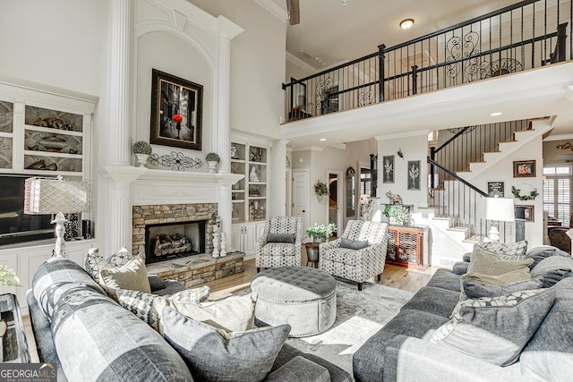 2930 Aquitania Ln, Cumming, GA 30040 - living area featuring wood finished floors, stairs, a stone fireplace, a high ceiling, and crown molding