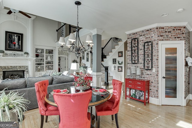 2930 Aquitania Ln, Cumming, GA 30040 - dining room featuring a fireplace, stairway, light wood finished floors, and ceiling fan with notable chandelier