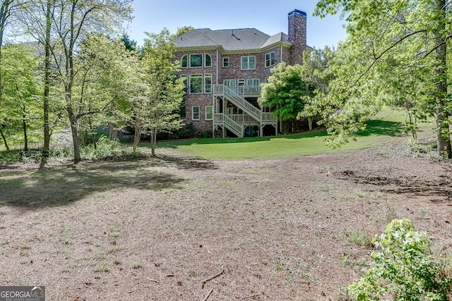 2930 Aquitania Ln, Cumming, GA 30040 - back of house with stairs, a wooden deck, a chimney, a yard, and brick siding