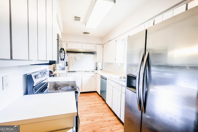 7415 Sierra Dr, Columbus, GA 31904 - kitchen featuring appliances with stainless steel finishes, light countertops, white cabinets, light wood-type flooring, and visible vents